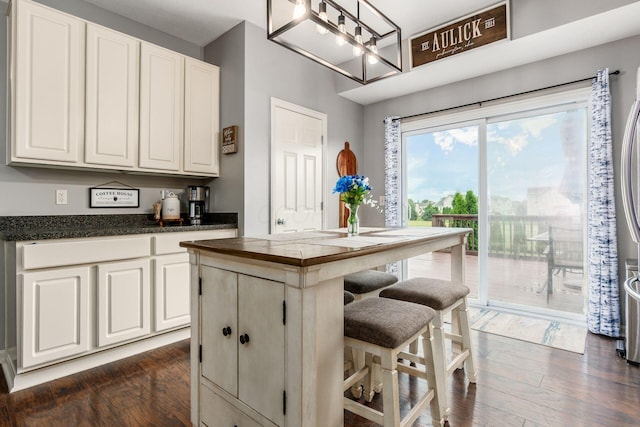 784 Brevard Cir, Pickerington, OH 43147 - kitchen featuring dark countertops, dark wood-type flooring, white cabinetry, and a kitchen bar