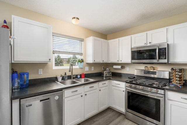 208 Dowler Dr, South Bloomfield, OH 43103 - kitchen featuring stainless steel appliances, dark countertops, wood finished floors, and white cabinets