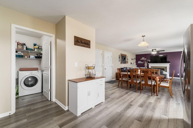 208 Dowler Dr, South Bloomfield, OH 43103 - kitchen with washer / dryer, wood finished floors, ceiling fan, freestanding refrigerator, and white cabinetry