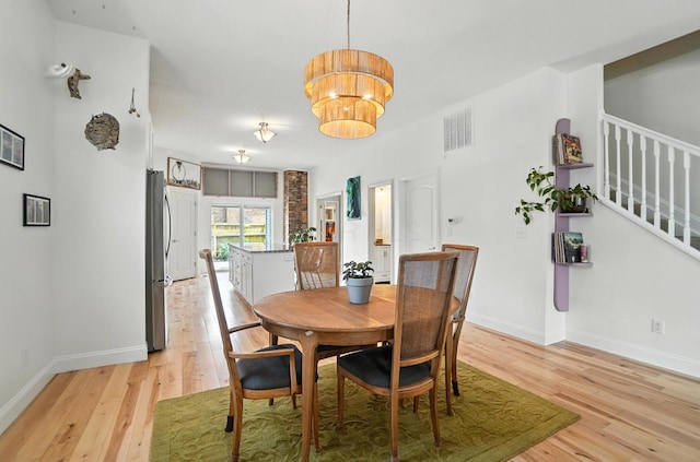 192 E Morrill Ave, Columbus, OH 43207 - dining space with light wood-style flooring, stairs, and a chandelier