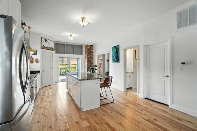 192 E Morrill Ave, Columbus, OH 43207 - kitchen featuring freestanding refrigerator, a breakfast bar area, light wood-style floors, and white cabinetry
