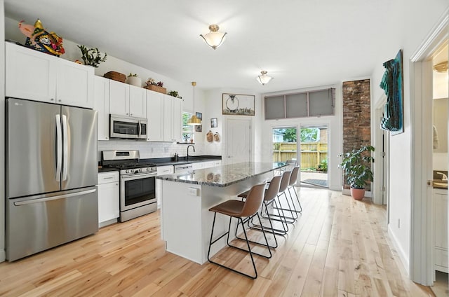 192 E Morrill Ave, Columbus, OH 43207 - kitchen featuring stainless steel appliances, a kitchen bar, tasteful backsplash, and light wood-style floors