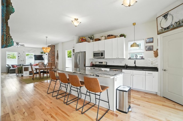 192 E Morrill Ave, Columbus, OH 43207 - kitchen with appliances with stainless steel finishes, a kitchen breakfast bar, tasteful backsplash, a kitchen island, and light wood-type flooring