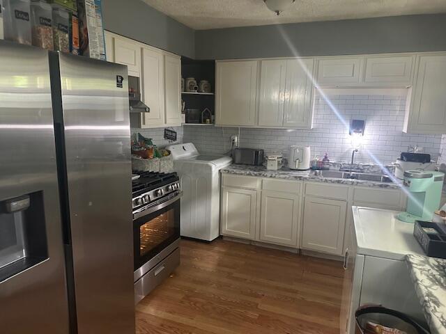 3519 Ontario St, Columbus, OH 43224 - kitchen featuring appliances with stainless steel finishes, washer / dryer, backsplash, and white cabinets