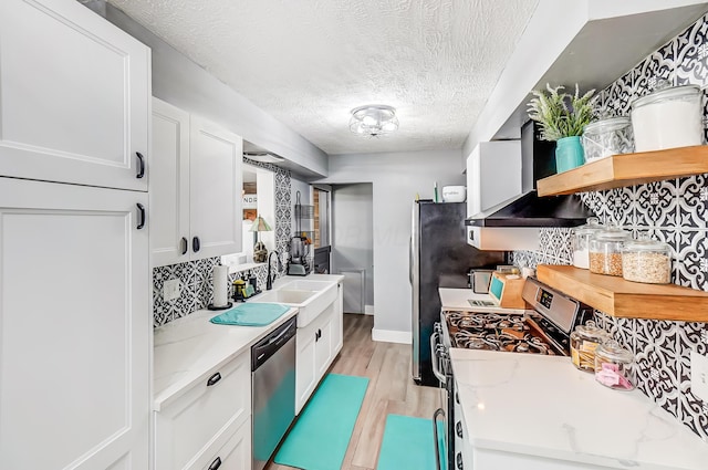 599 S Brinker Ave, Columbus, OH 43204 - kitchen featuring stainless steel appliances, wall chimney exhaust hood, open shelves, white cabinets, and light wood-style floors