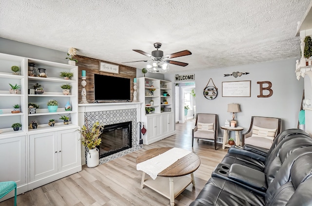 599 S Brinker Ave, Columbus, OH 43204 - living room with a tile fireplace, a textured ceiling, a ceiling fan, and light wood-type flooring