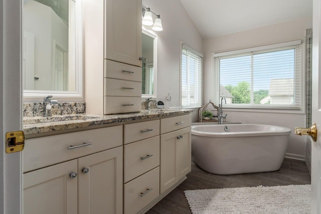 333 Quarter Way, Delaware, OH 43015 - bathroom featuring lofted ceiling, wood finished floors, double vanity, and a freestanding tub
