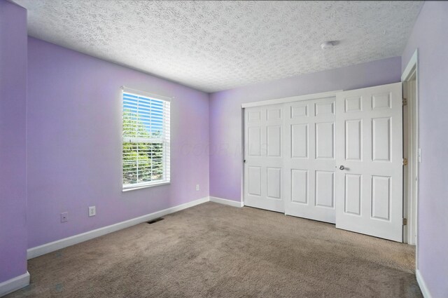 1812 Bennigan Dr Unit 88C, Hilliard, OH 43026 - unfurnished bedroom featuring carpet, a closet, and a textured ceiling