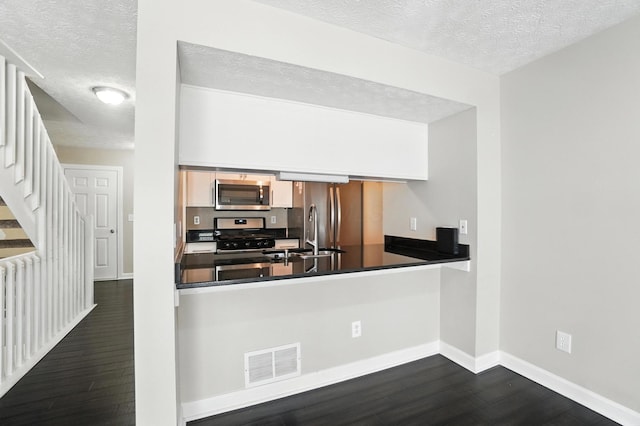 1812 Bennigan Dr Unit 88C, Hilliard, OH 43026 - kitchen with appliances with stainless steel finishes, dark wood finished floors, a textured ceiling, dark countertops, and a peninsula