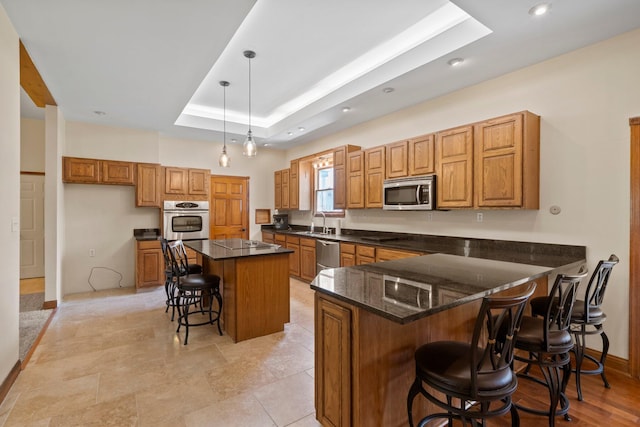 5373 Summit Rd SW, Pataskala, OH 43062 - kitchen with stainless steel appliances, brown cabinetry, a raised ceiling, a kitchen bar, and a kitchen island