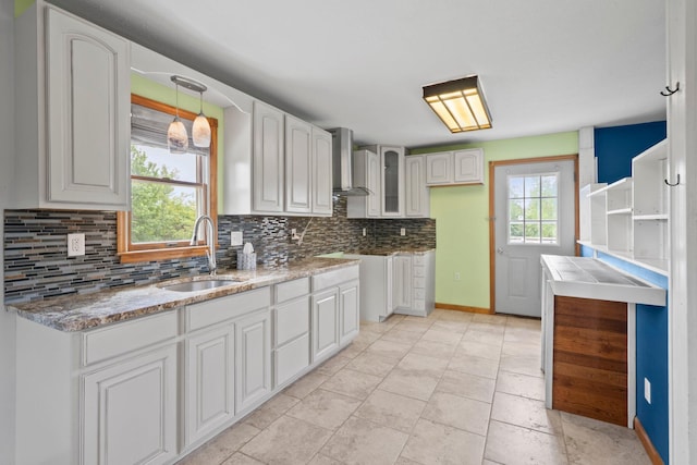 5373 Summit Rd SW, Pataskala, OH 43062 - kitchen featuring wall chimney range hood, tasteful backsplash, white cabinets, glass insert cabinets, and light stone countertops