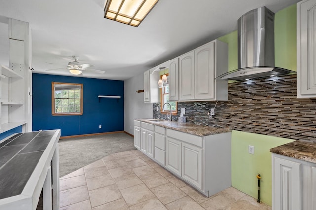 5373 Summit Rd SW, Pataskala, OH 43062 - kitchen featuring wall chimney range hood, light colored carpet, a ceiling fan, white cabinets, and backsplash