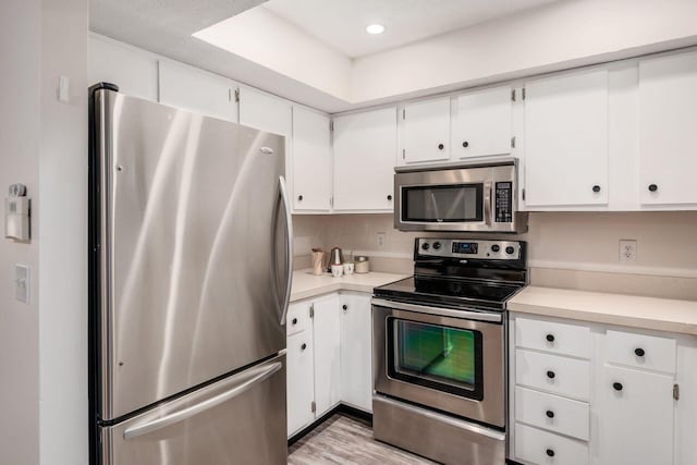 7911 Verandah Ct Unit 58, Powell, OH 43065 - kitchen with stainless steel appliances, light countertops, white cabinetry, and light wood-style flooring
