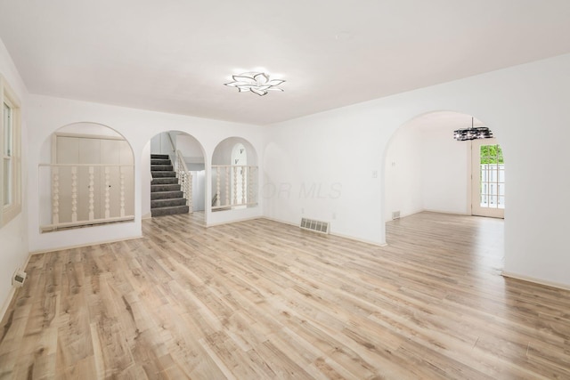 1571 Vinton Ave, Columbus, OH 43220 - empty room with arched walkways, wood finished floors, stairs, and a chandelier