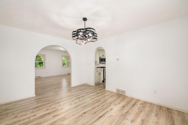 1571 Vinton Ave, Columbus, OH 43220 - empty room with a chandelier, arched walkways, and light wood-style floors