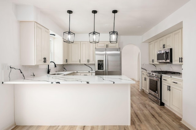1571 Vinton Ave, Columbus, OH 43220 - kitchen with appliances with stainless steel finishes, tasteful backsplash, arched walkways, a peninsula, and light wood finished floors
