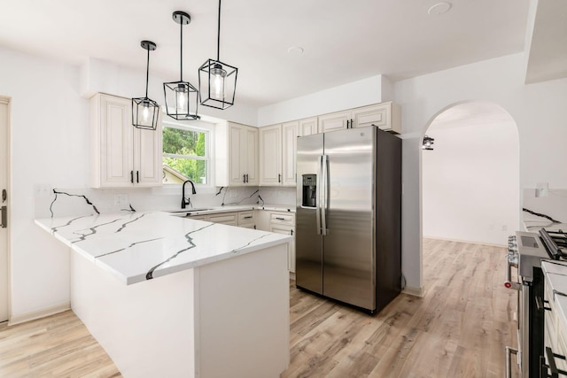 1571 Vinton Ave, Columbus, OH 43220 - kitchen featuring appliances with stainless steel finishes, a peninsula, arched walkways, light stone counters, and light wood finished floors