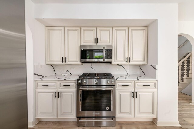 1571 Vinton Ave, Columbus, OH 43220 - kitchen with appliances with stainless steel finishes, arched walkways, backsplash, and light stone countertops