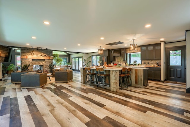 1300 Dannie Dr, Logan, OH 43138 - kitchen with light countertops, a spacious island, a stone fireplace, tasteful backsplash, and recessed lighting