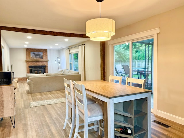 3811 Bradford Dr, Hilliard, OH 43026 - dining room with wood finished floors, healthy amount of natural light, a brick fireplace, beam ceiling, and recessed lighting