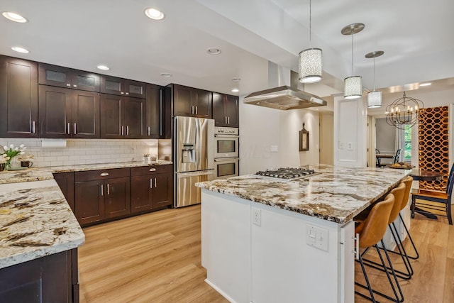 1318 Hickory Ridge Ln, Columbus, OH 43235 - kitchen with stainless steel appliances, island range hood, light wood-style floors, a breakfast bar, and light stone counters