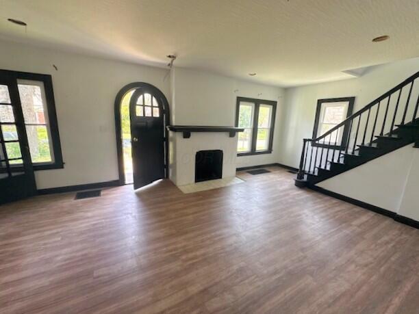 959 Kelton Ave, Columbus, OH 43206 - unfurnished living room with wood finished floors, healthy amount of natural light, stairs, and a fireplace with flush hearth