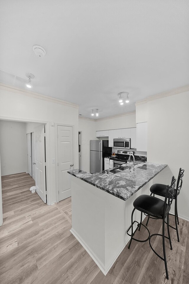 25 Victorian Gate Way, Columbus, OH 43215 - kitchen with stainless steel appliances, crown molding, white cabinetry, a kitchen breakfast bar, and a peninsula