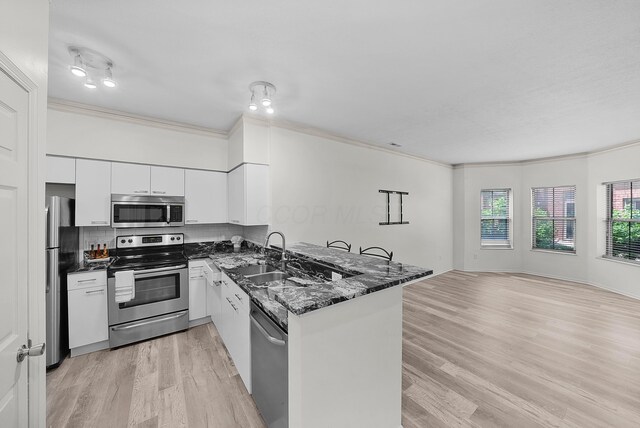 25 Victorian Gate Way, Columbus, OH 43215 - kitchen with stainless steel appliances, crown molding, a peninsula, light wood-style floors, and white cabinetry
