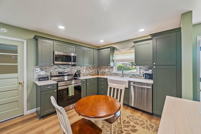 320 W Liberty St, Bucyrus, OH 44820 - kitchen featuring stainless steel appliances, light countertops, green cabinetry, decorative backsplash, and recessed lighting