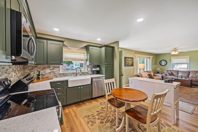 320 W Liberty St, Bucyrus, OH 44820 - kitchen with green cabinets, dishwasher, electric range, backsplash, and light wood-style floors