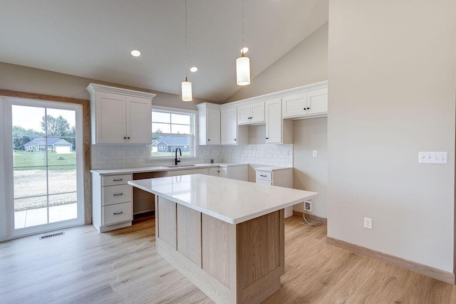 551 Cannondale Ave, Johnstown, OH 43031 - kitchen featuring a center island, decorative backsplash, light wood-style floors, white cabinets, and hanging light fixtures