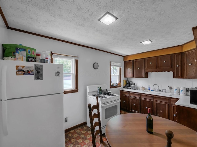 1018 Harrison Ave, Lancaster, OH 43130 - kitchen featuring white appliances, healthy amount of natural light, light countertops, crown molding, and dark brown cabinets