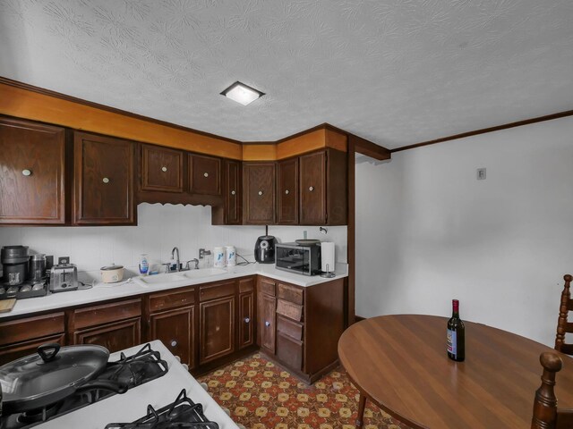 1018 Harrison Ave, Lancaster, OH 43130 - kitchen featuring light countertops, dark brown cabinets, crown molding, and gas range oven