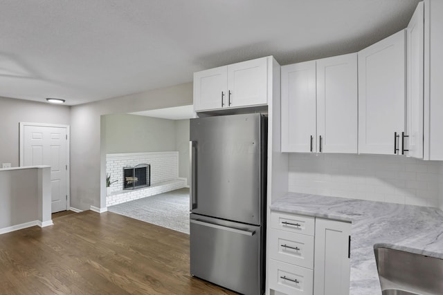 3171 Haskell Dr, Columbus, OH 43219 - kitchen with freestanding refrigerator, white cabinets, a fireplace, light stone countertops, and decorative backsplash