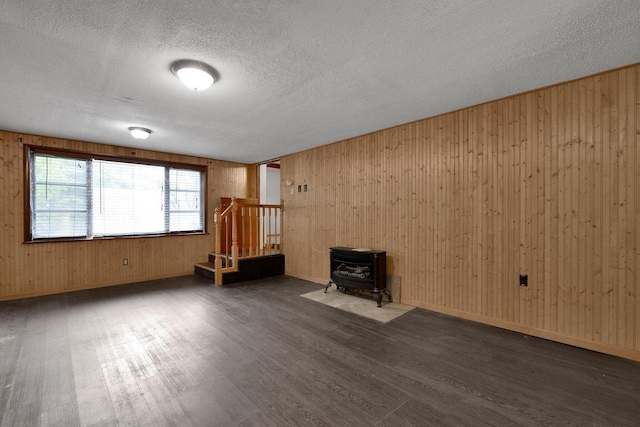 3166 Howey Rd, Columbus, OH 43224 - unfurnished living room with a wood stove, wood finished floors, a textured ceiling, and wooden walls