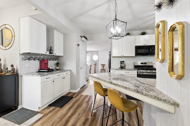 115 Maple Ave, Utica, OH 43080 - kitchen with gas stove, black microwave, tasteful backsplash, white cabinetry, and wood finished floors