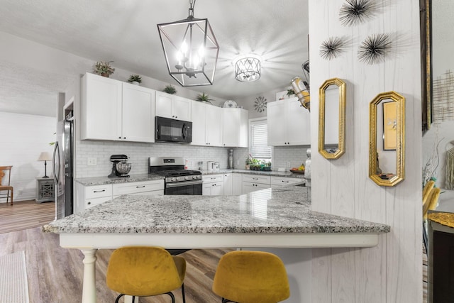 115 Maple Ave, Utica, OH 43080 - kitchen featuring stainless steel appliances, white cabinetry, a kitchen breakfast bar, and light wood-type flooring