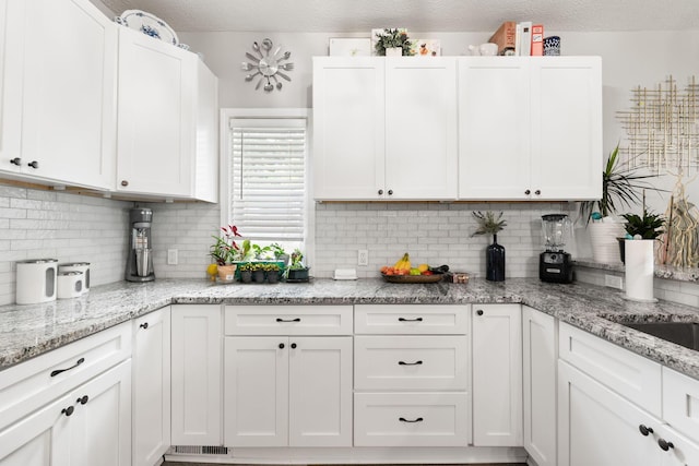 115 Maple Ave, Utica, OH 43080 - kitchen featuring backsplash, white cabinets, and light stone counters
