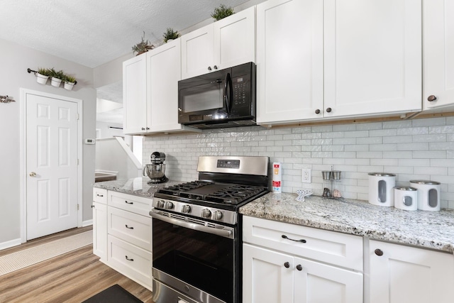 115 Maple Ave, Utica, OH 43080 - kitchen with stainless steel gas stove, black microwave, light wood-style flooring, white cabinets, and tasteful backsplash