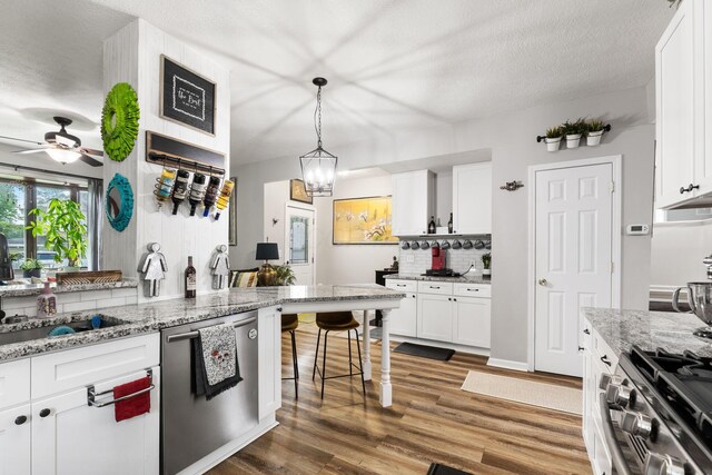 115 Maple Ave, Utica, OH 43080 - kitchen featuring stainless steel appliances, ceiling fan, wood finished floors, white cabinetry, and a textured ceiling