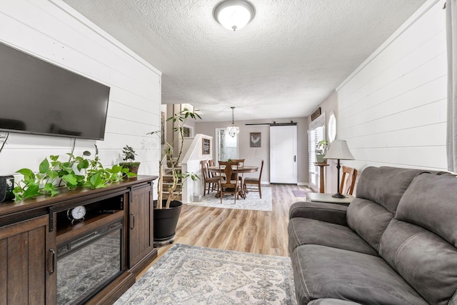 115 Maple Ave, Utica, OH 43080 - living room featuring a textured ceiling, wood walls, light wood finished floors, and a barn door