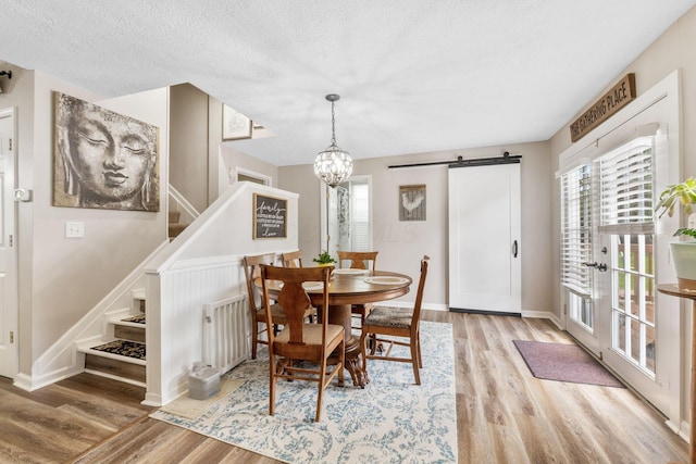 115 Maple Ave, Utica, OH 43080 - dining area with a barn door, wood finished floors, stairway, a chandelier, and a textured ceiling