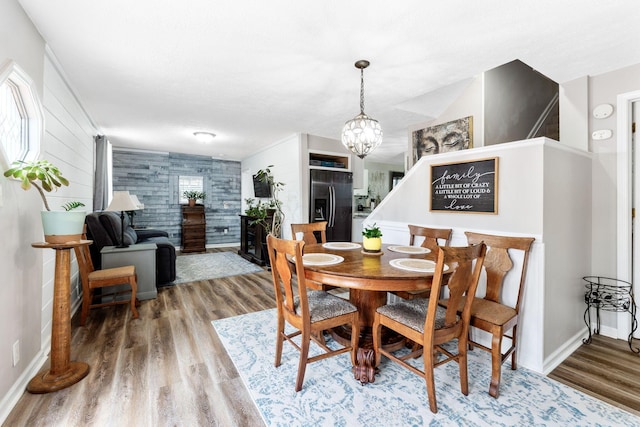 115 Maple Ave, Utica, OH 43080 - dining space with wood finished floors, a chandelier, an accent wall, and wood walls