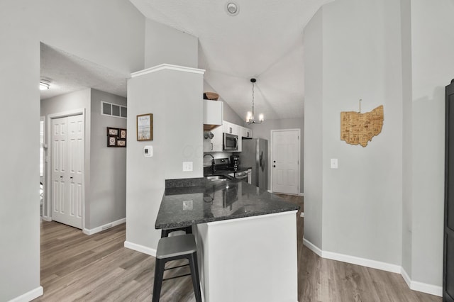 7838 Kiowa Way, Columbus, OH 43085 - kitchen featuring appliances with stainless steel finishes, a breakfast bar area, white cabinetry, light wood-type flooring, and dark stone counters