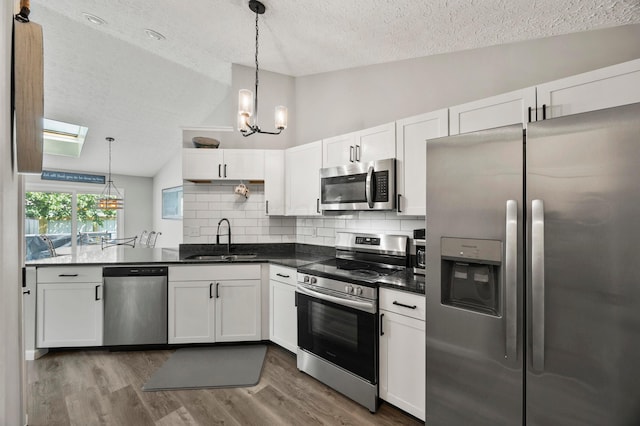 7838 Kiowa Way, Columbus, OH 43085 - kitchen featuring appliances with stainless steel finishes, a textured ceiling, lofted ceiling, dark countertops, and white cabinets