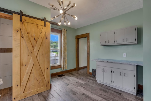 522 S Main St, New Lexington, OH 43764 - kitchen featuring light countertops, wood finished floors, a barn door, white cabinets, and a chandelier