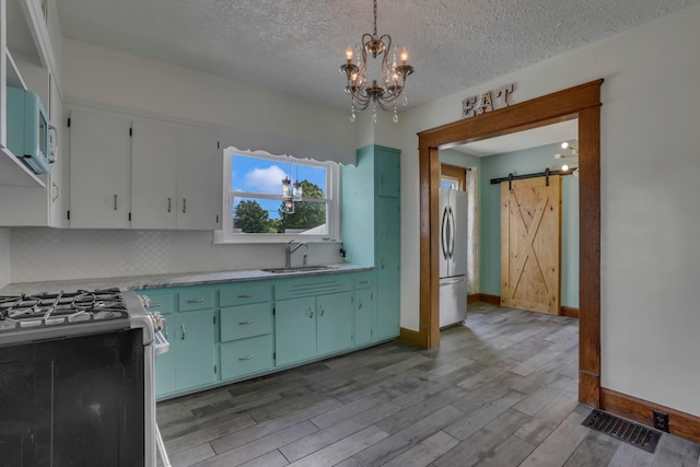 522 S Main St, New Lexington, OH 43764 - kitchen featuring stainless steel gas range, freestanding refrigerator, a barn door, light countertops, and tasteful backsplash