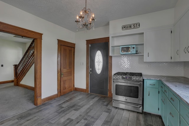 522 S Main St, New Lexington, OH 43764 - kitchen with stainless steel range with gas stovetop, white microwave, a chandelier, wood finished floors, and a textured ceiling