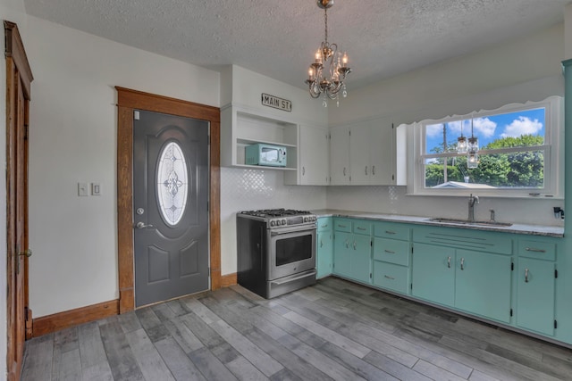 522 S Main St, New Lexington, OH 43764 - kitchen with gas stove, white microwave, a chandelier, a textured ceiling, and light wood finished floors