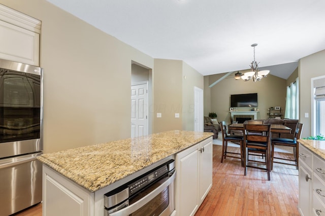 13191 Brandon Cir, Pickerington, OH 43147 - kitchen with fridge, light wood finished floors, light stone countertops, a chandelier, and white cabinetry